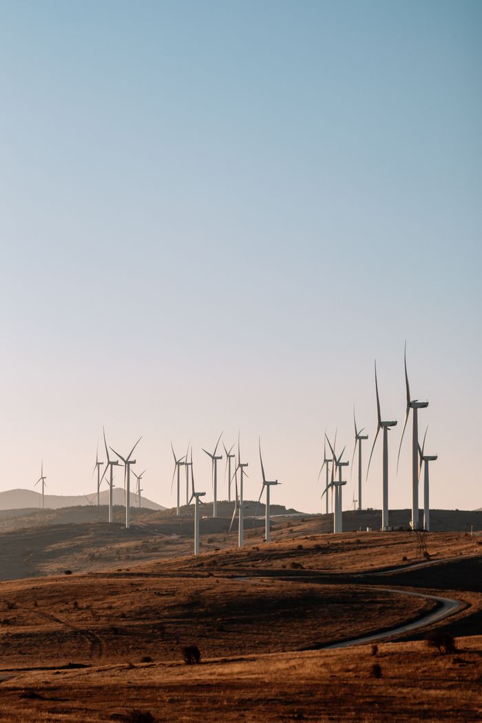 The Art of Drawing Readers In: Your attractive post title goes here Wind turbines on a rolling landscape at sunset with clear blue sky.